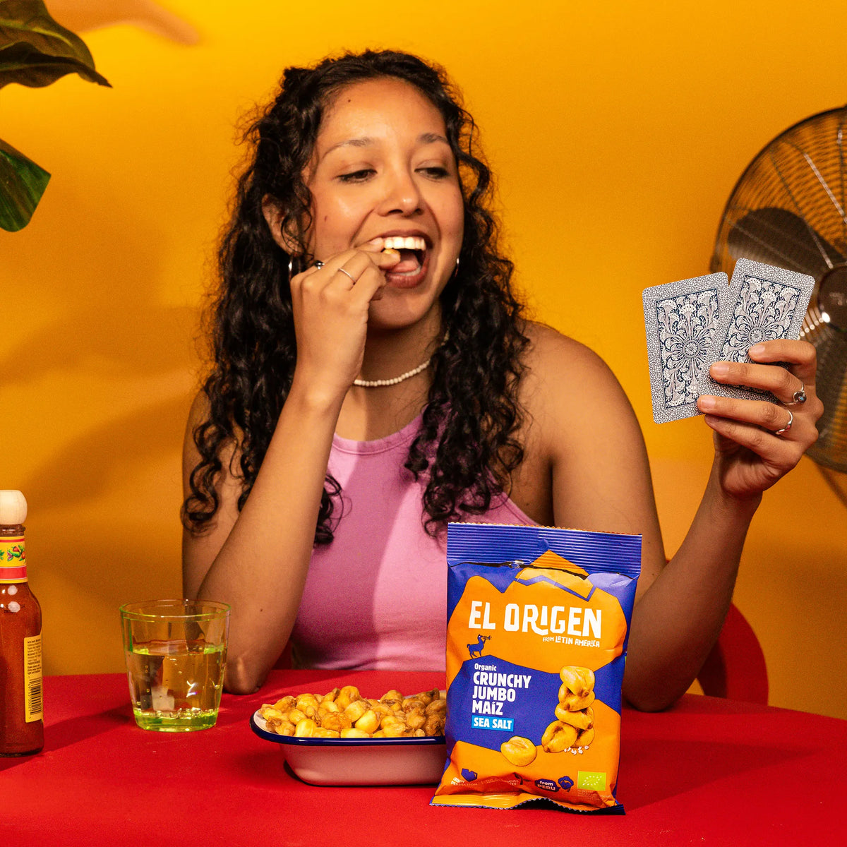 Frau snackt el origen Crunchy Jumbo Maíz aus einer Schale neben der Packung